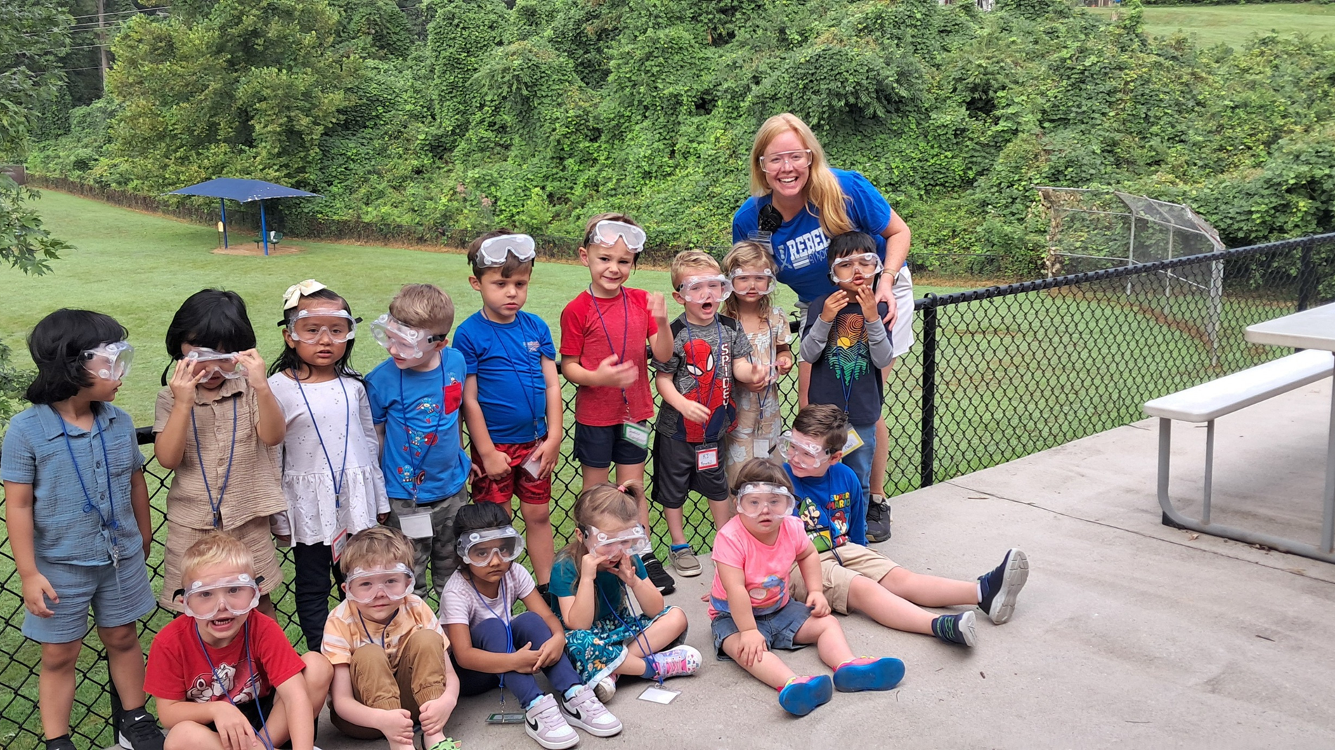 Students stop for a group picture in their safety goggles with Mrs. Arp.