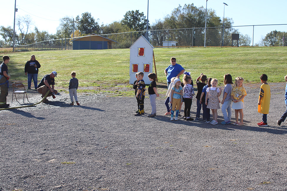 Fire Fighter Andrew Russell helps students with the fire hose