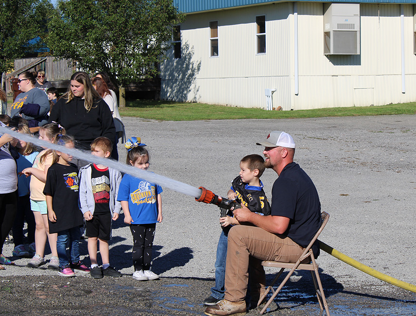 Fire Fighter Andrew Russell helps students with the fire hose