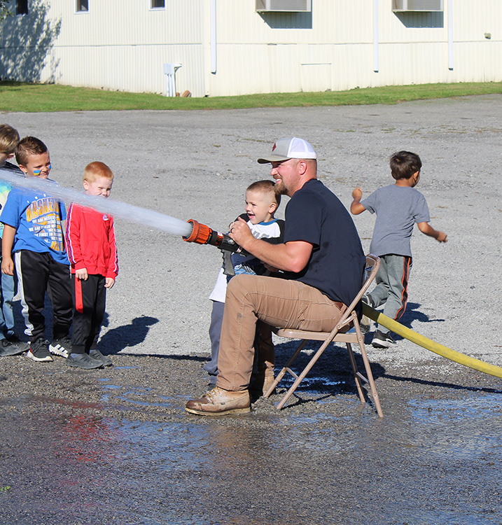 Fire Fighter Andrew Russell helps students with the fire hose