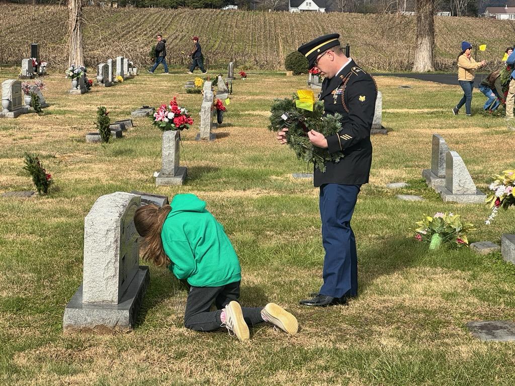 student place wreath at cemetery