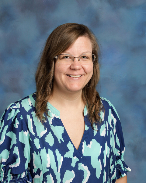 Teacher smiling against a blue background