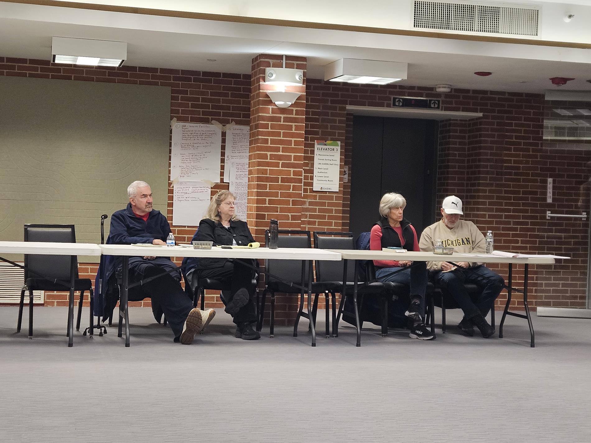 Four adult attendees sit at a table  listening to the presentation