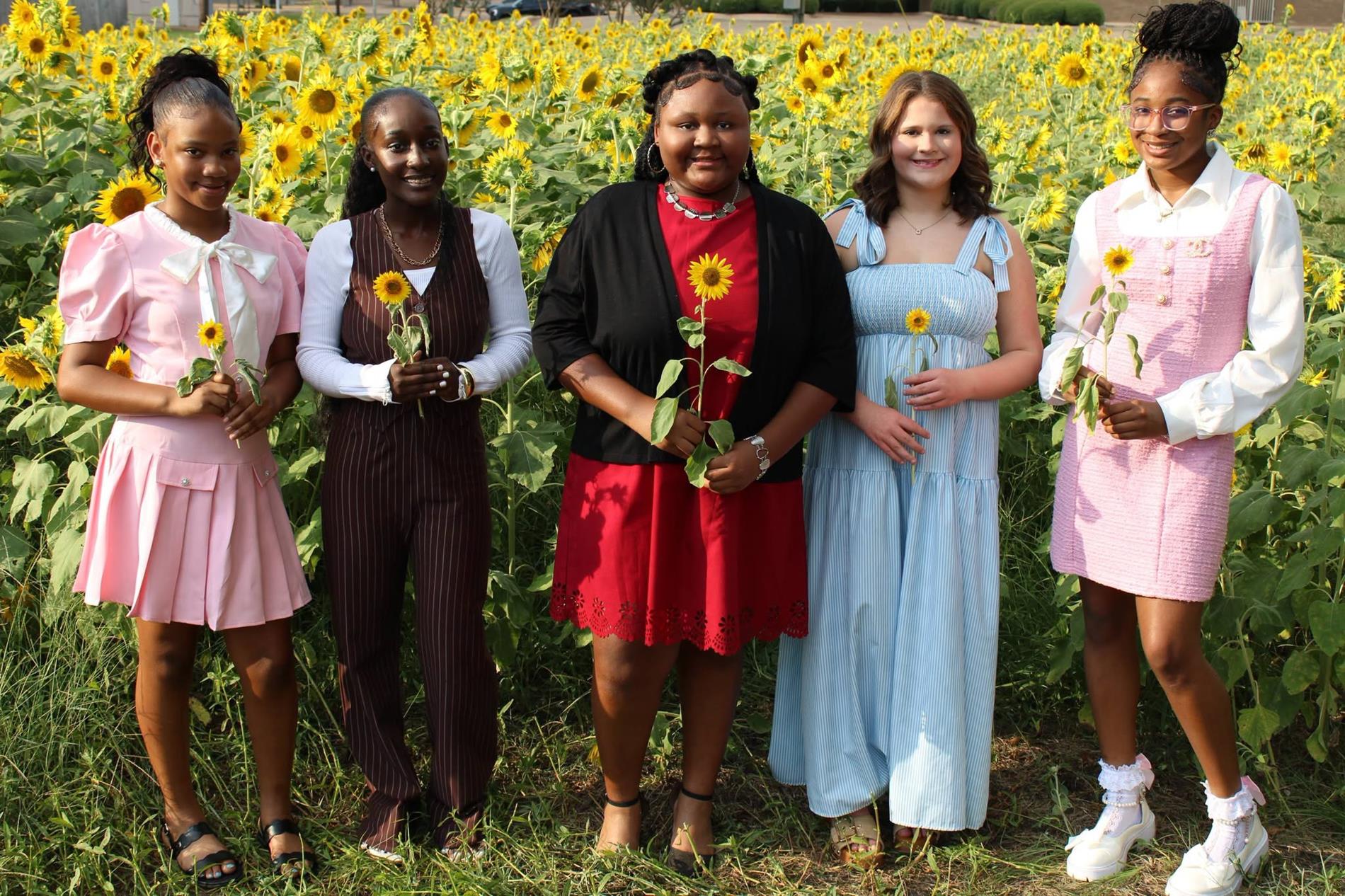 Fifth Street School 7th Grade Homecoming Maids pose together in a sunflower field while holding sunflowers.