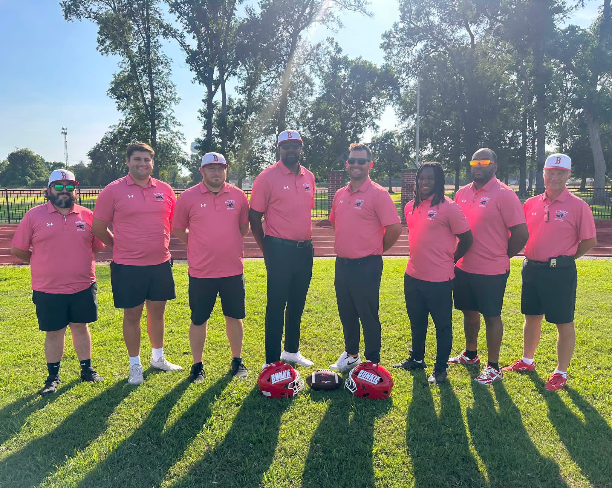 Bunkie football coaching staff together beside the field