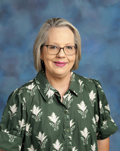 Teacher smiling against a blue background