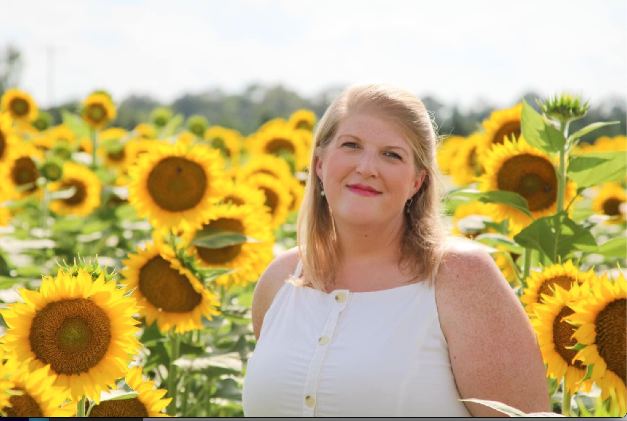 Mrs. Amanda standing in front of sunflowers