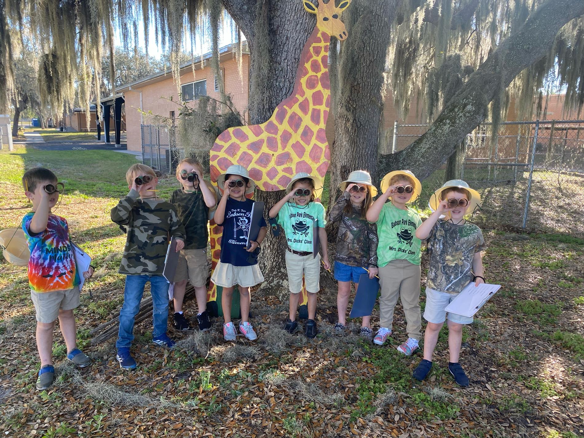 Kindergarten students standing in front of a giraffe. 