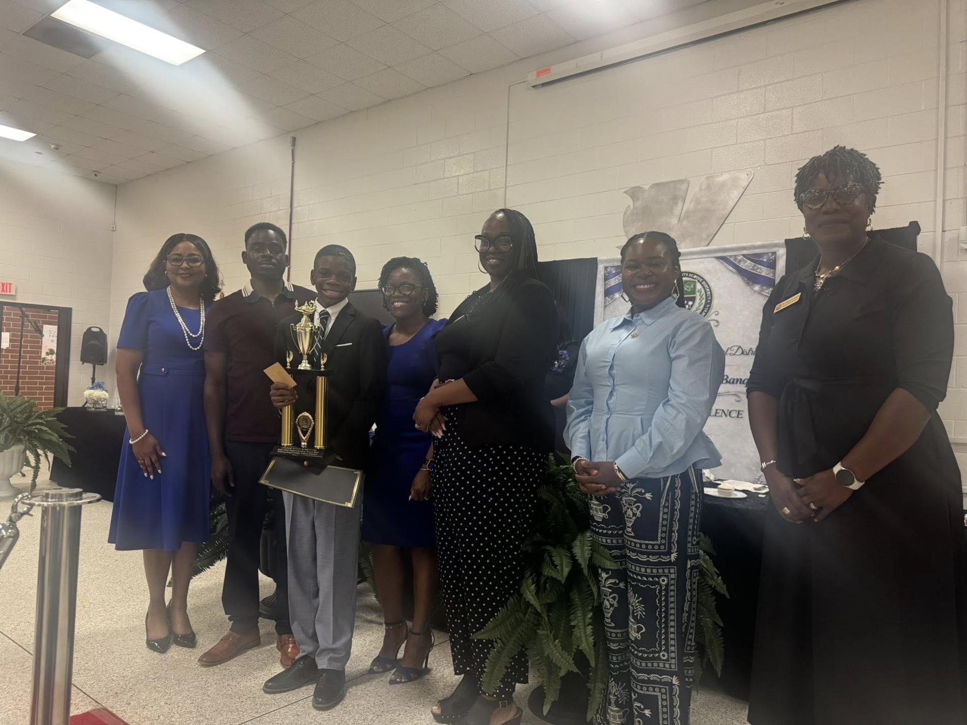 people standing together. one is receiving an award 