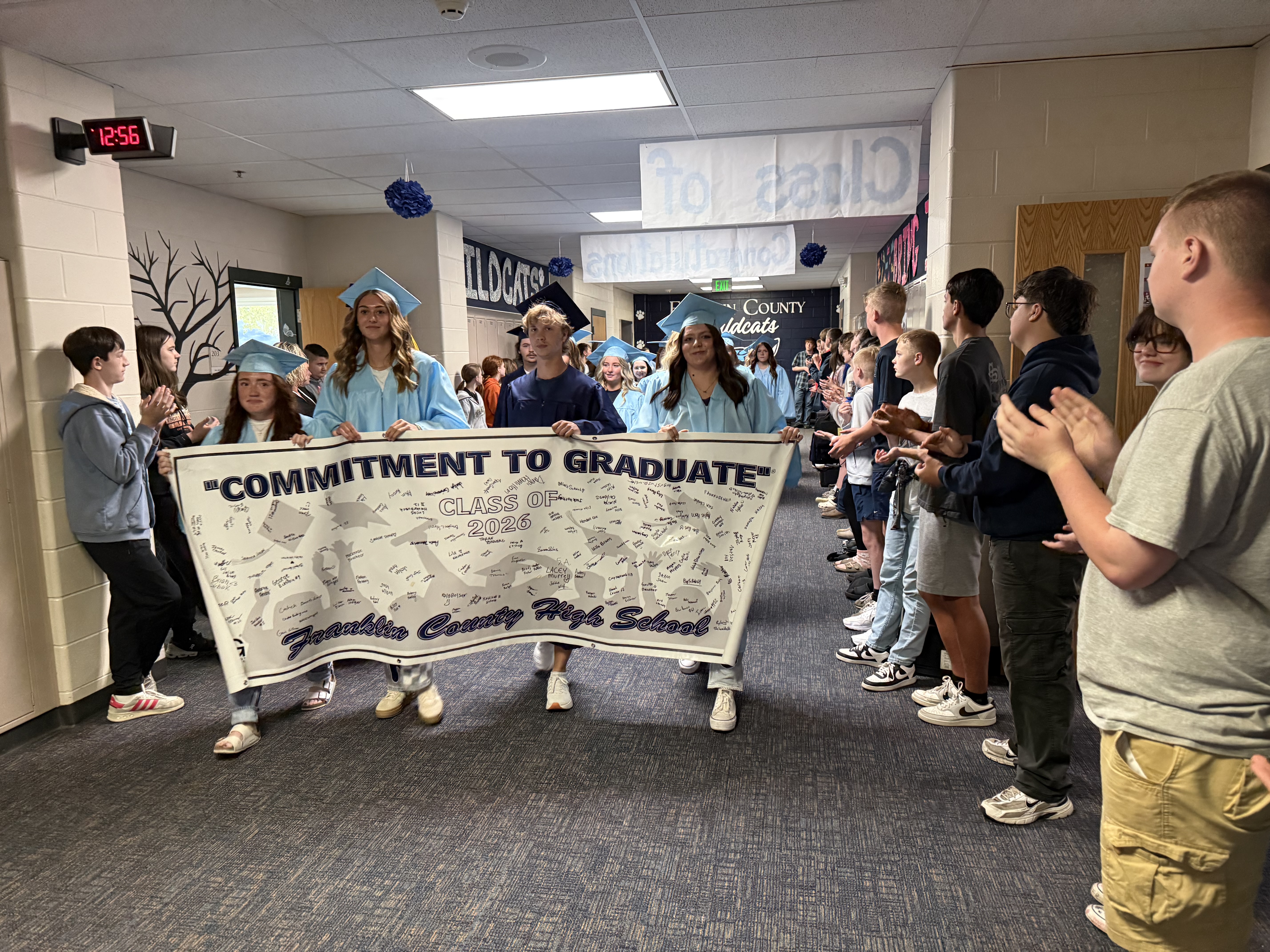 students cap and gown with sign