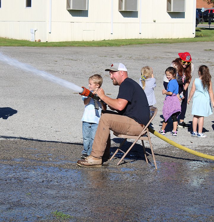 Fire Fighter Andrew Russell helps students with the fire hose