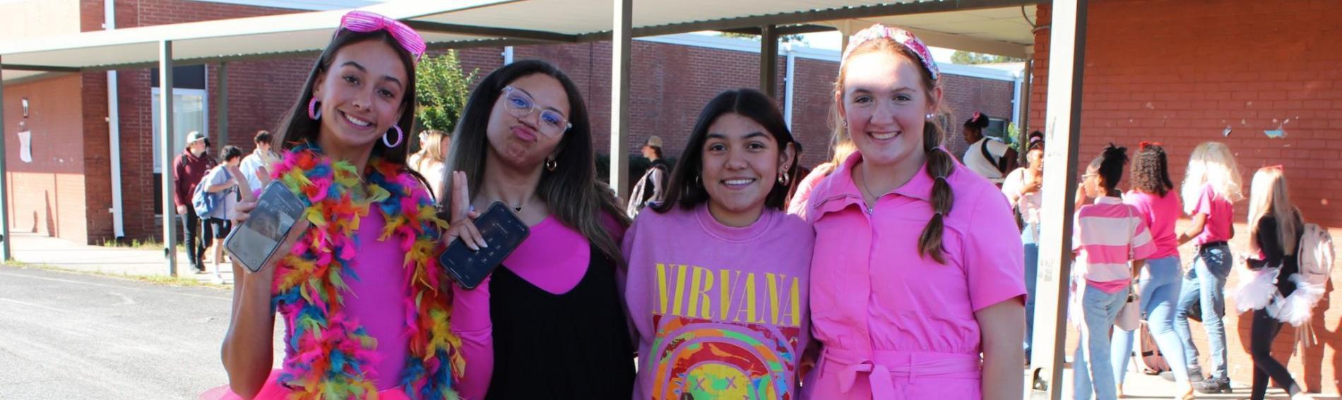 Four girls smile at the camera while wearing pink clothing to celebrate Pink Out Day