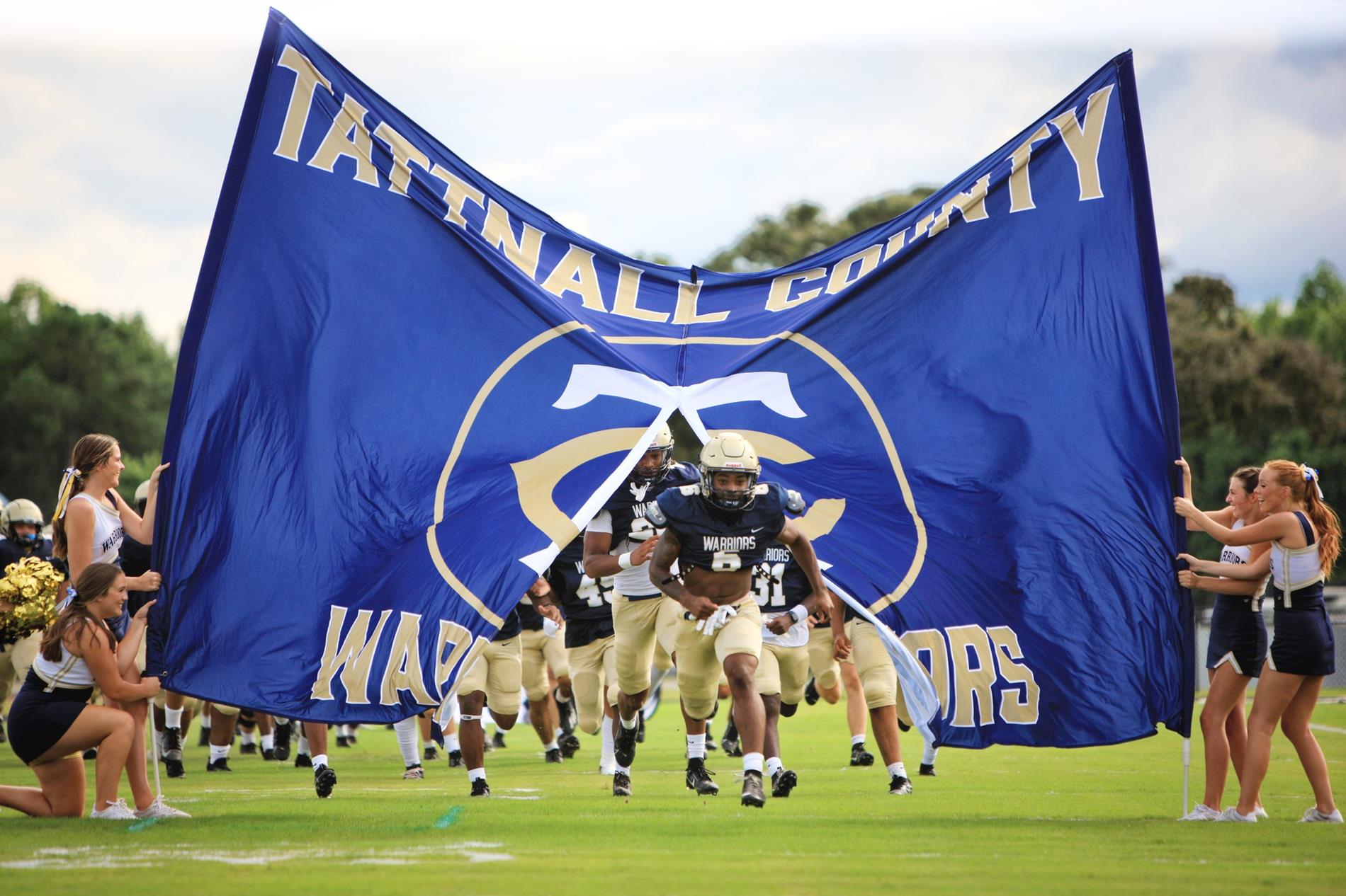 Football players coming through banner