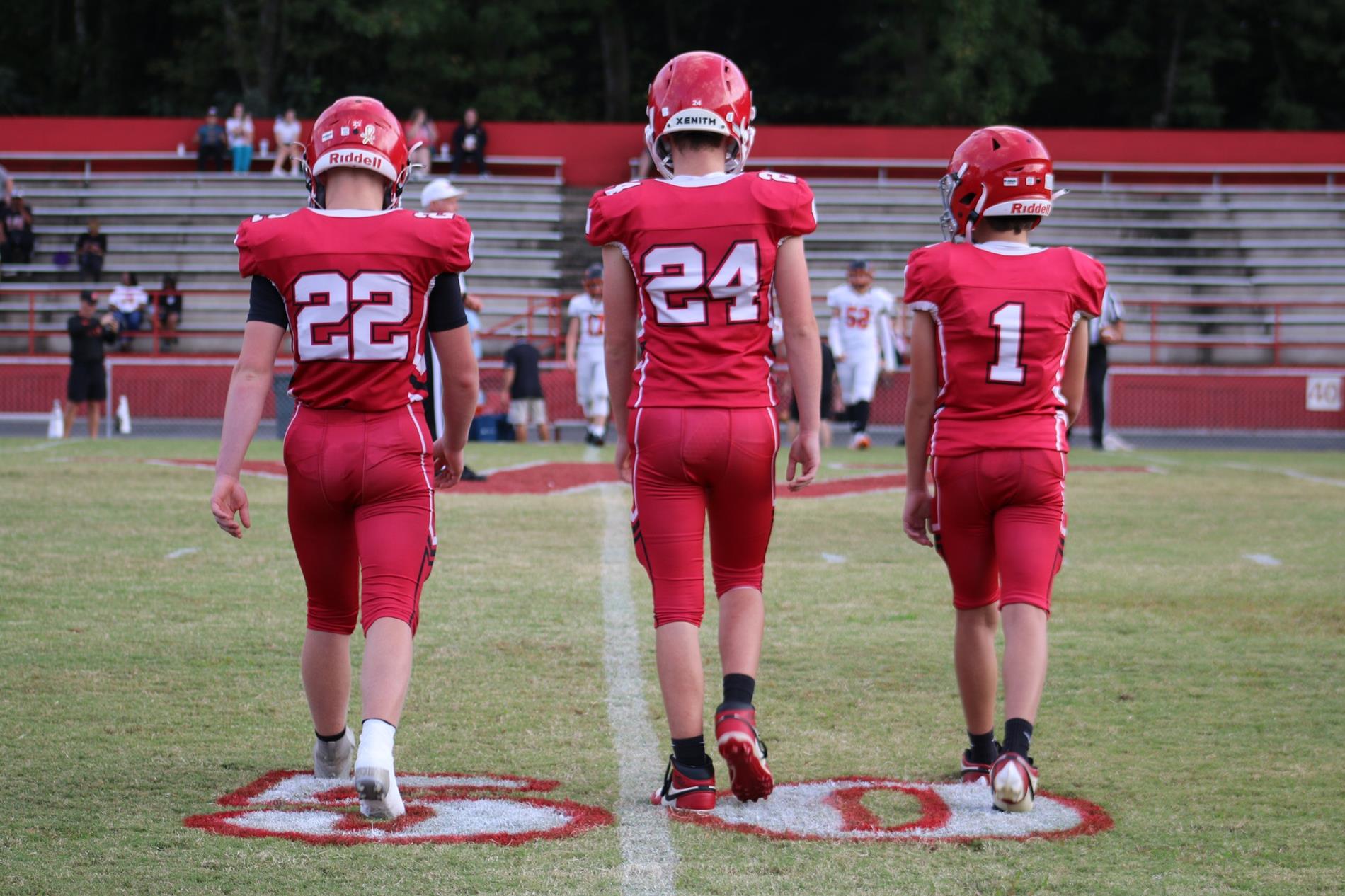 WMS football captains walking to meet refs at 50 yard line.
