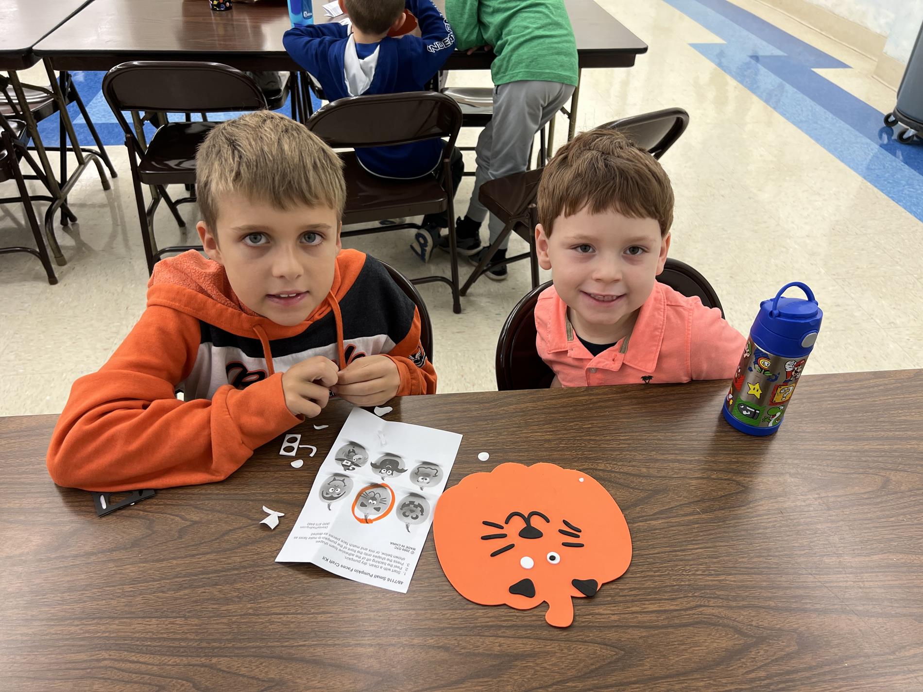 older student with younger student decorating a pumpkin
