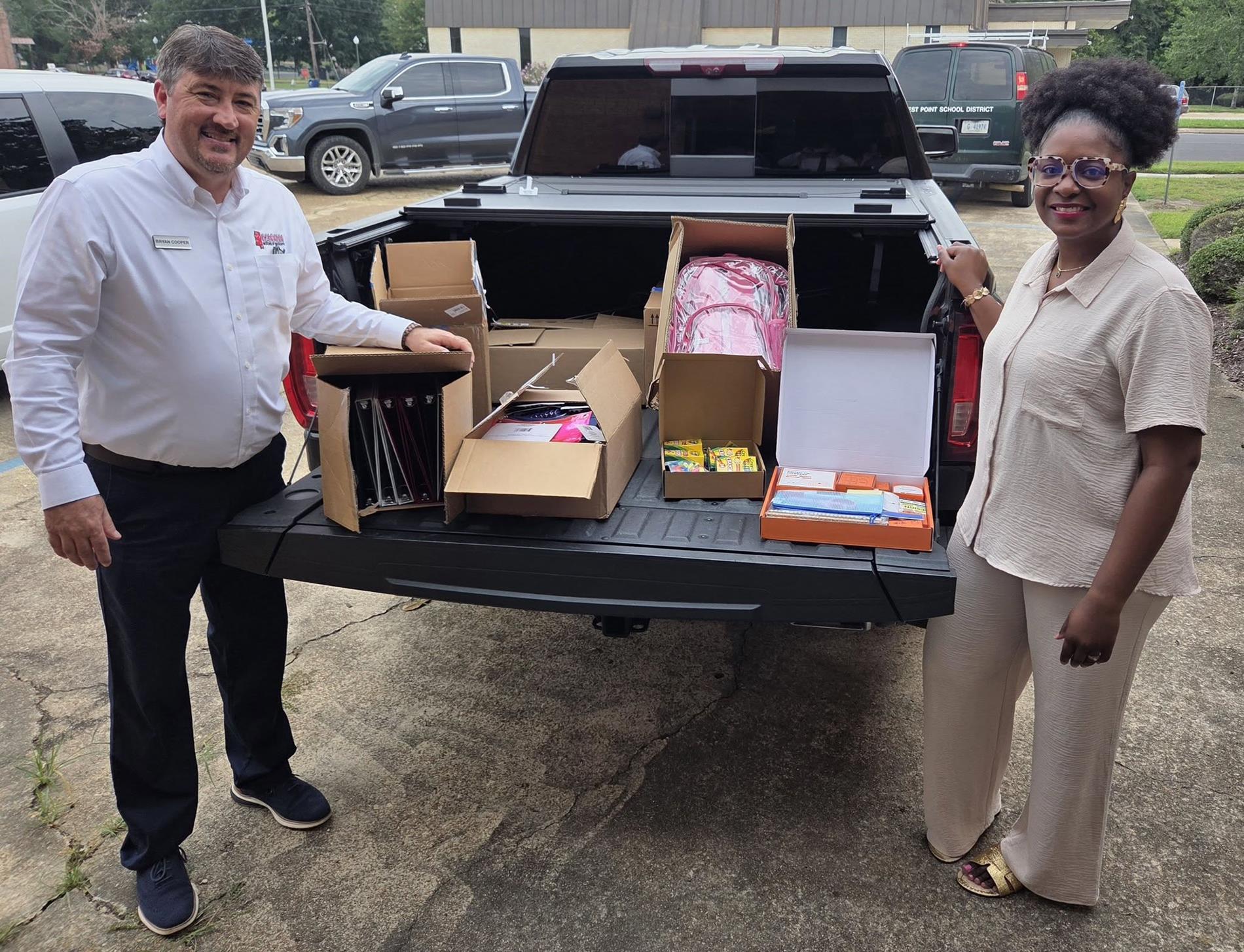 Representatives from Cannon Chevrolet GMC and West Point Consolidated School District display donated backpacks and school supplies for students.