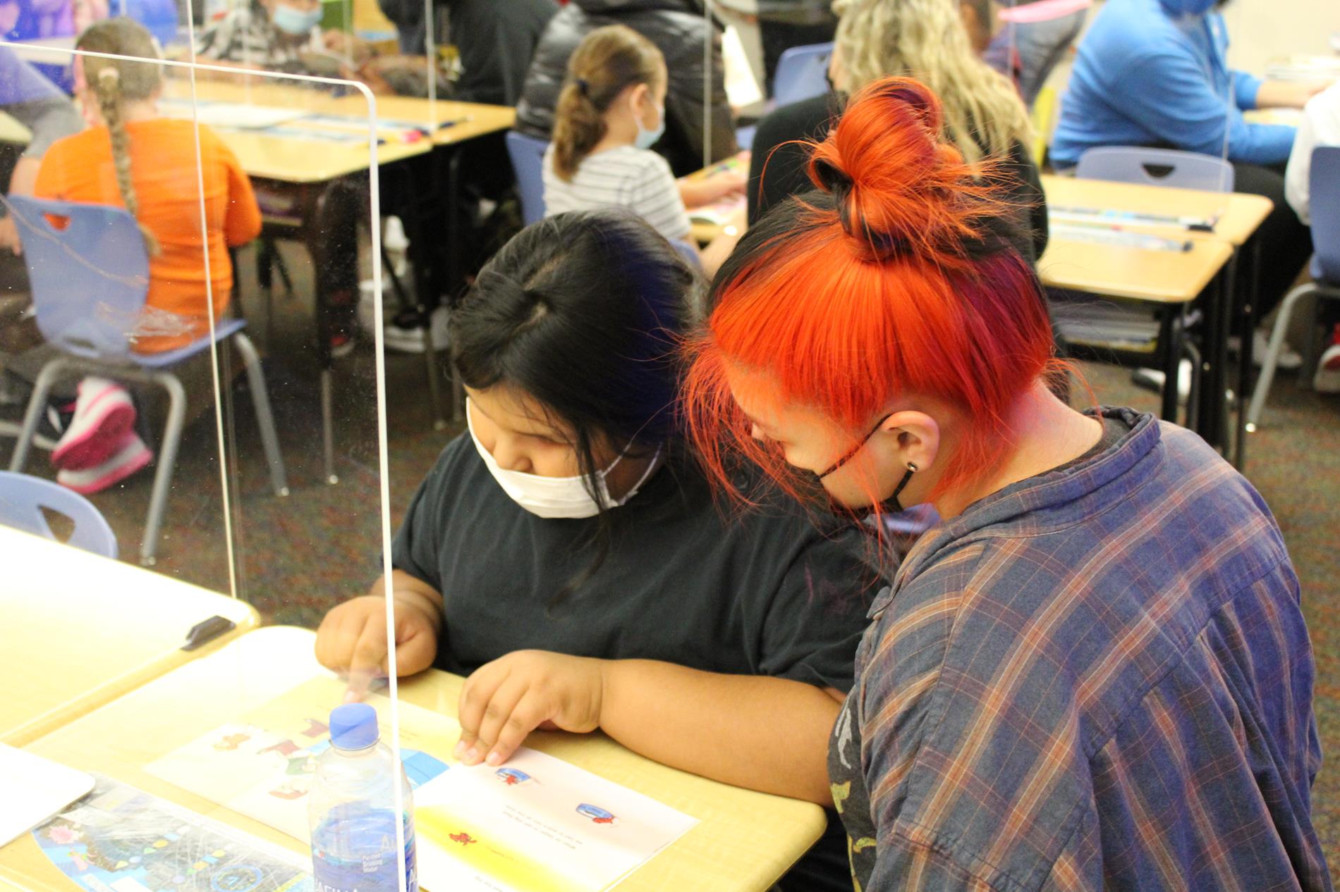 Junior high student reading to a kindergarten student