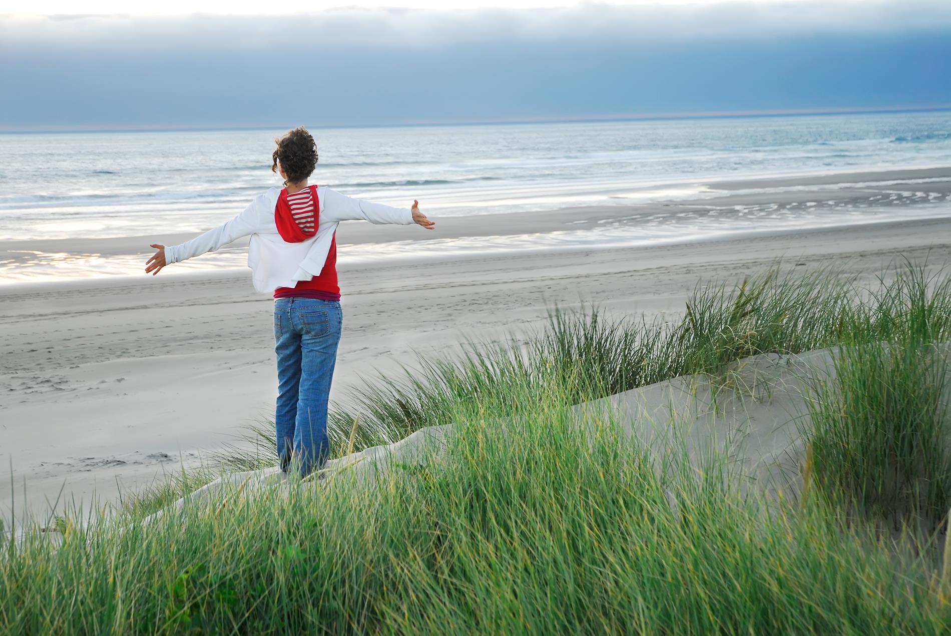 person on beach with arms stretched out wide
