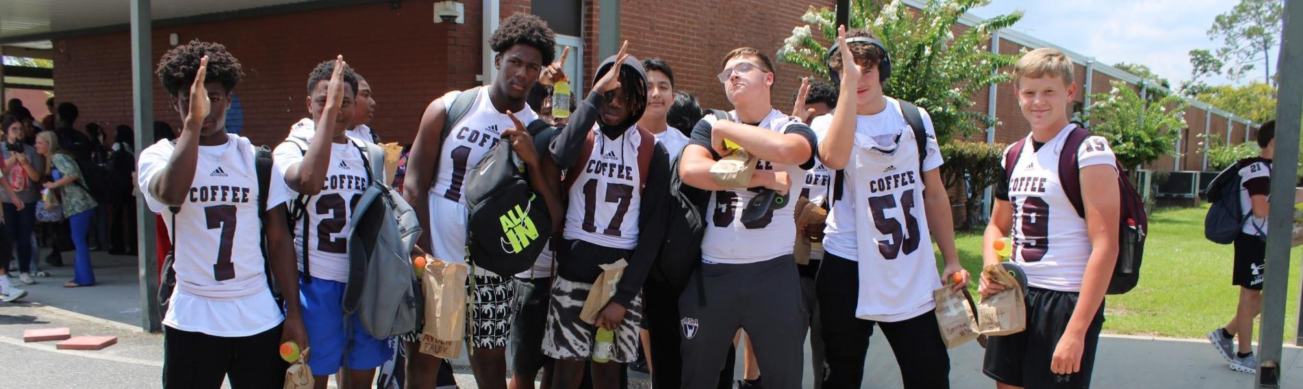 A group of boys in their football jerseys pose outside the school