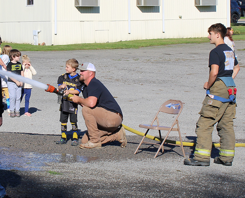 Fire Fighter Andrew Russell helps students with the fire hose