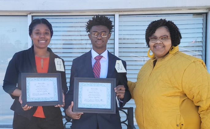 Two students pictured along with school counselor holding certificates for oratorical contest 