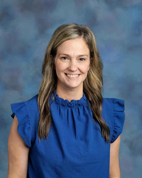Teacher smiling against a blue background
