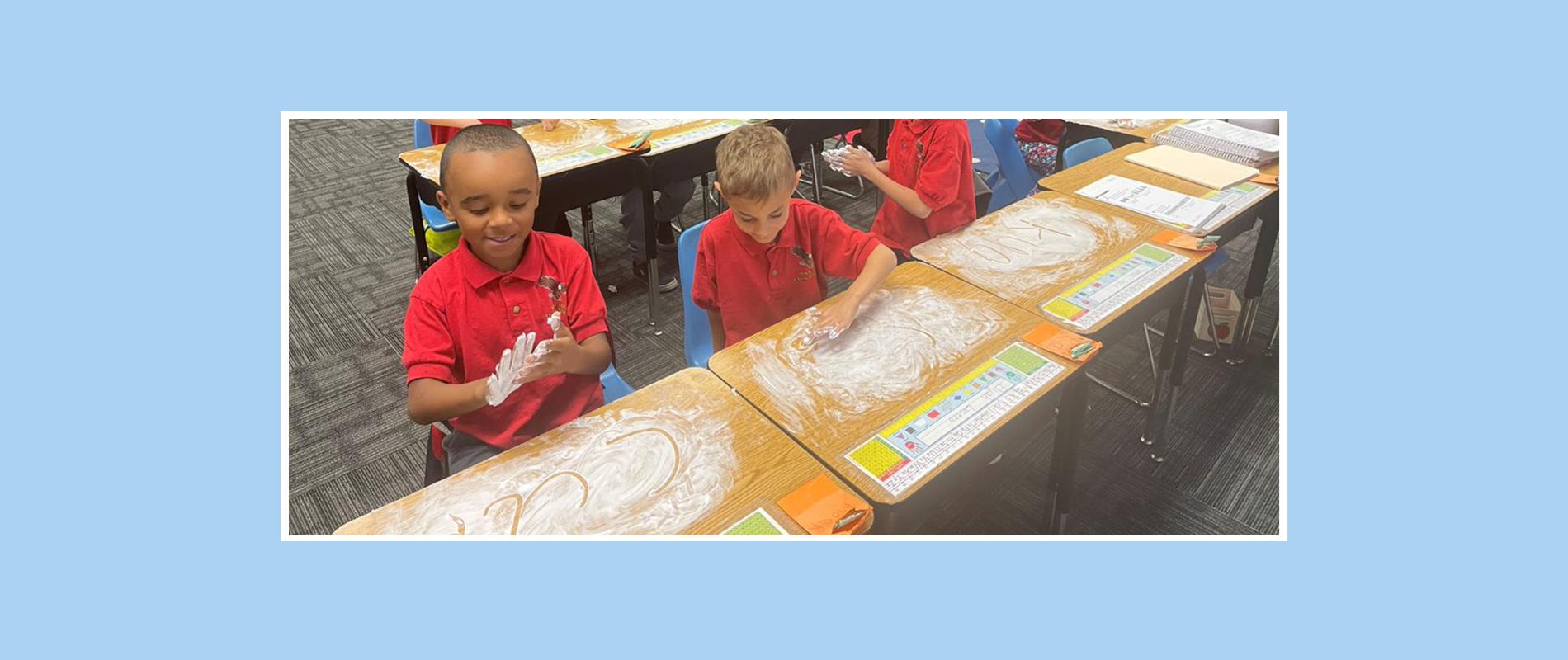 students writing in shaving cream on their desks