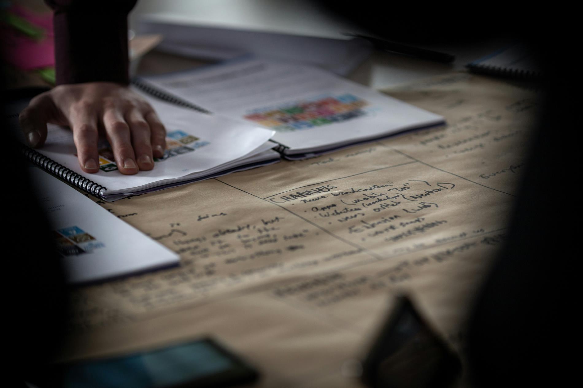 A man puts his hands on a table covered with strategy documents