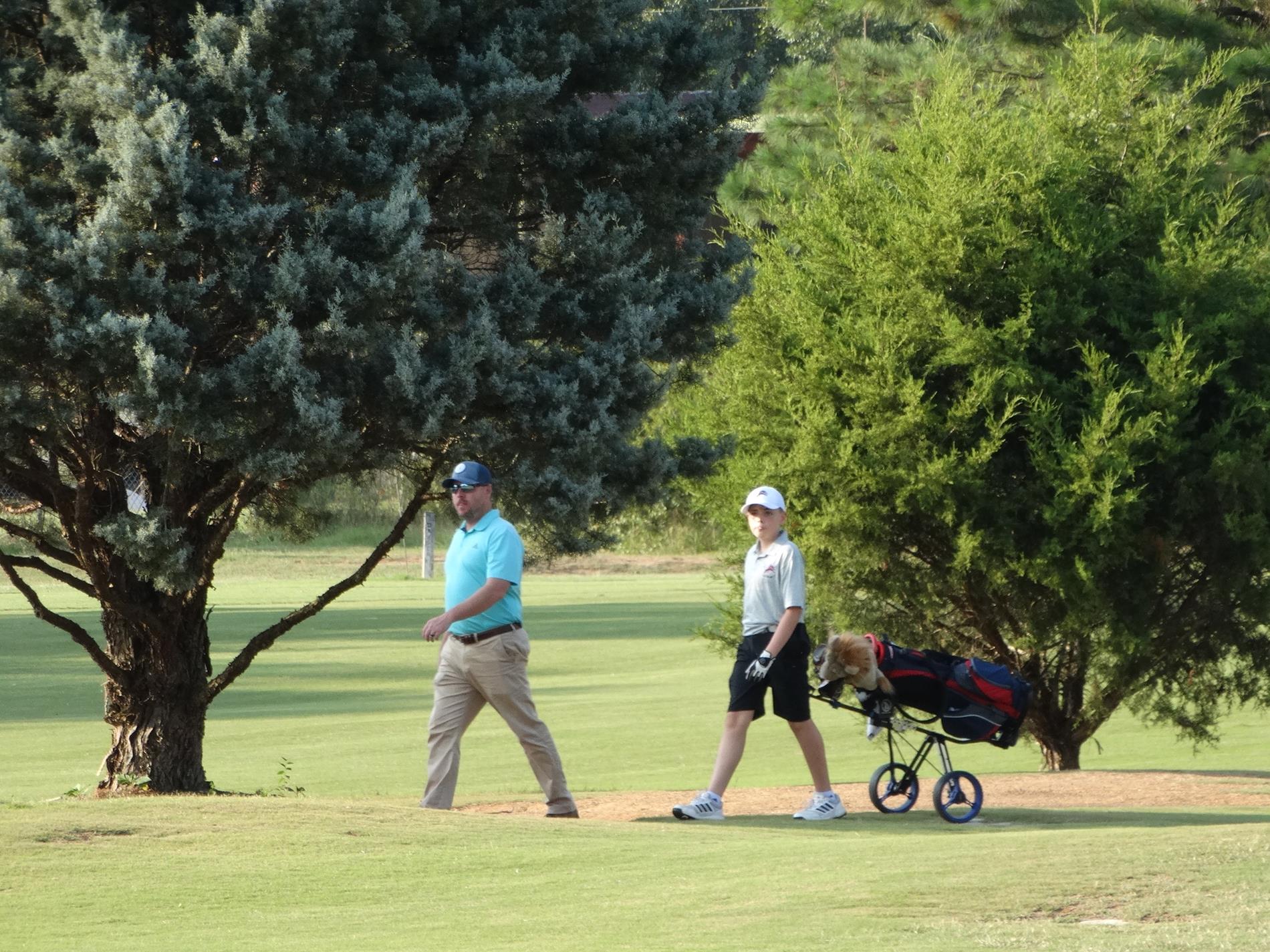 PIC OF SOMEONE PULLING THE GOLF CADDY ON GOLF COURSE