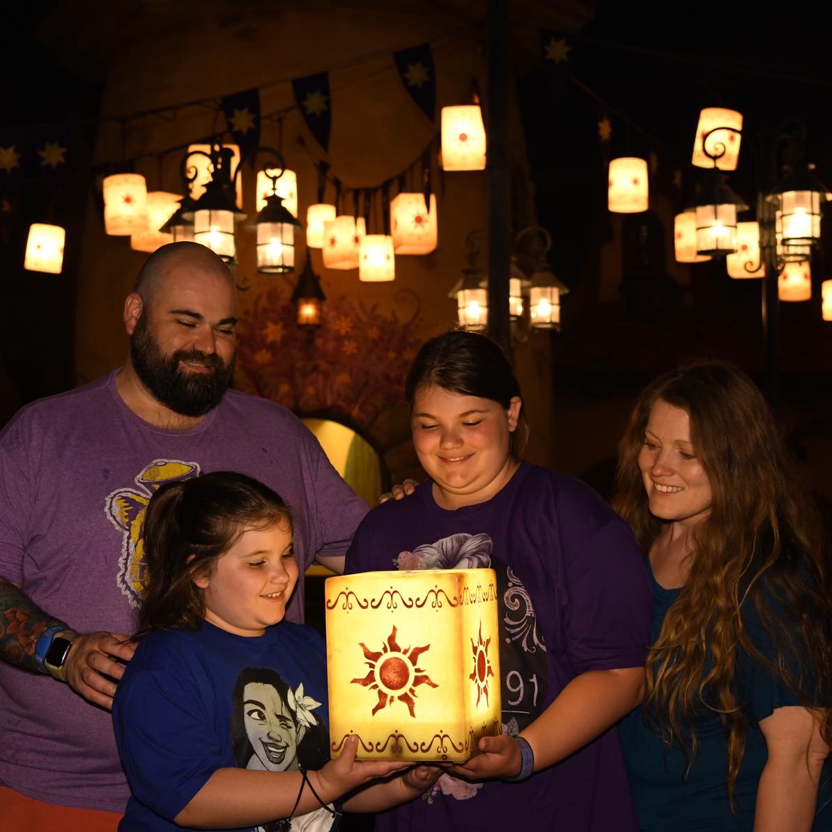 Family photo of Ms. G and family gathered around glowing lanterns at night