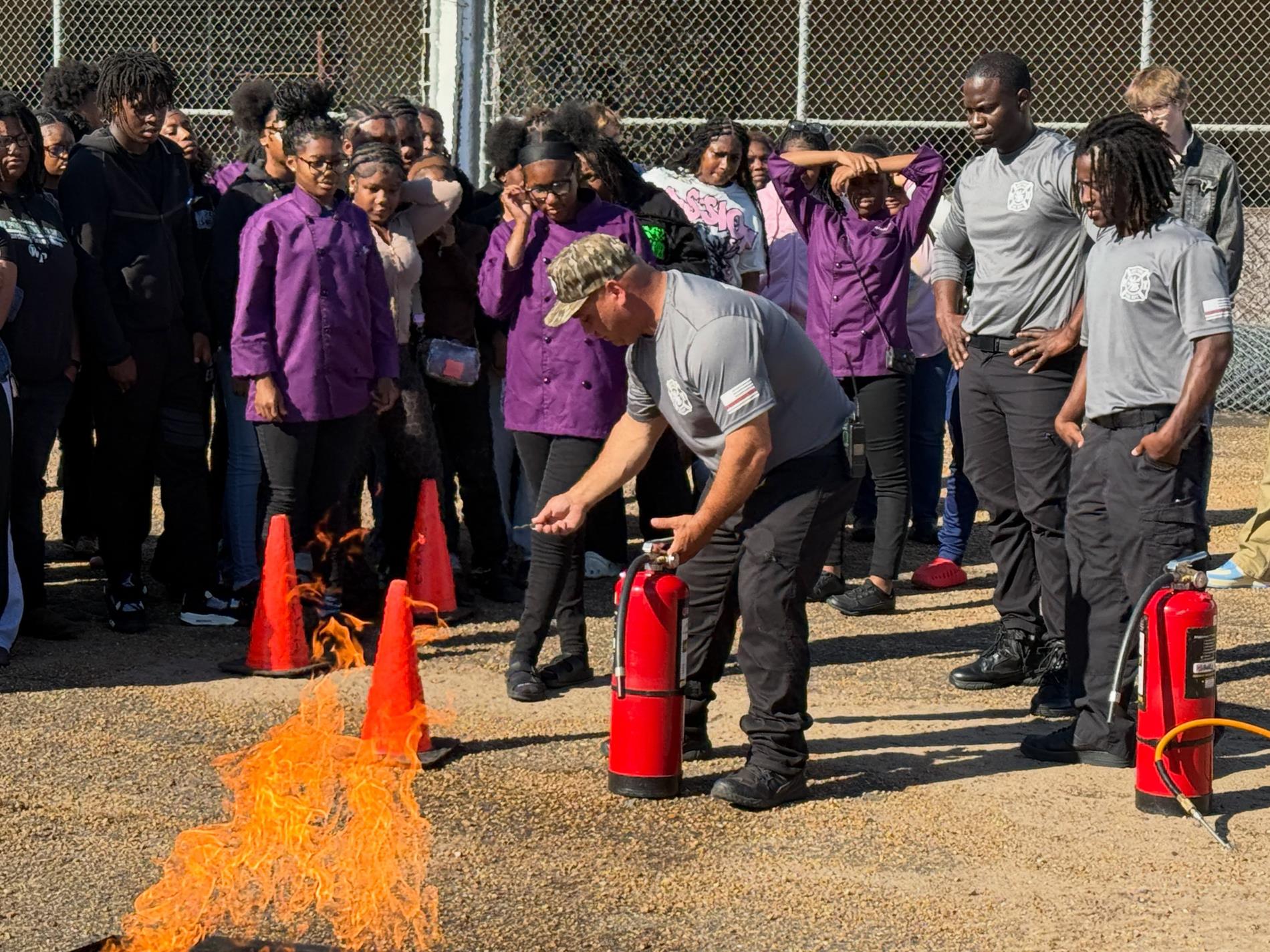 West Point Career & Technology Center students participate in hands-on fire safety training with West Point Fire Department personnel, including practice using fire extinguishers on a controlled fire.