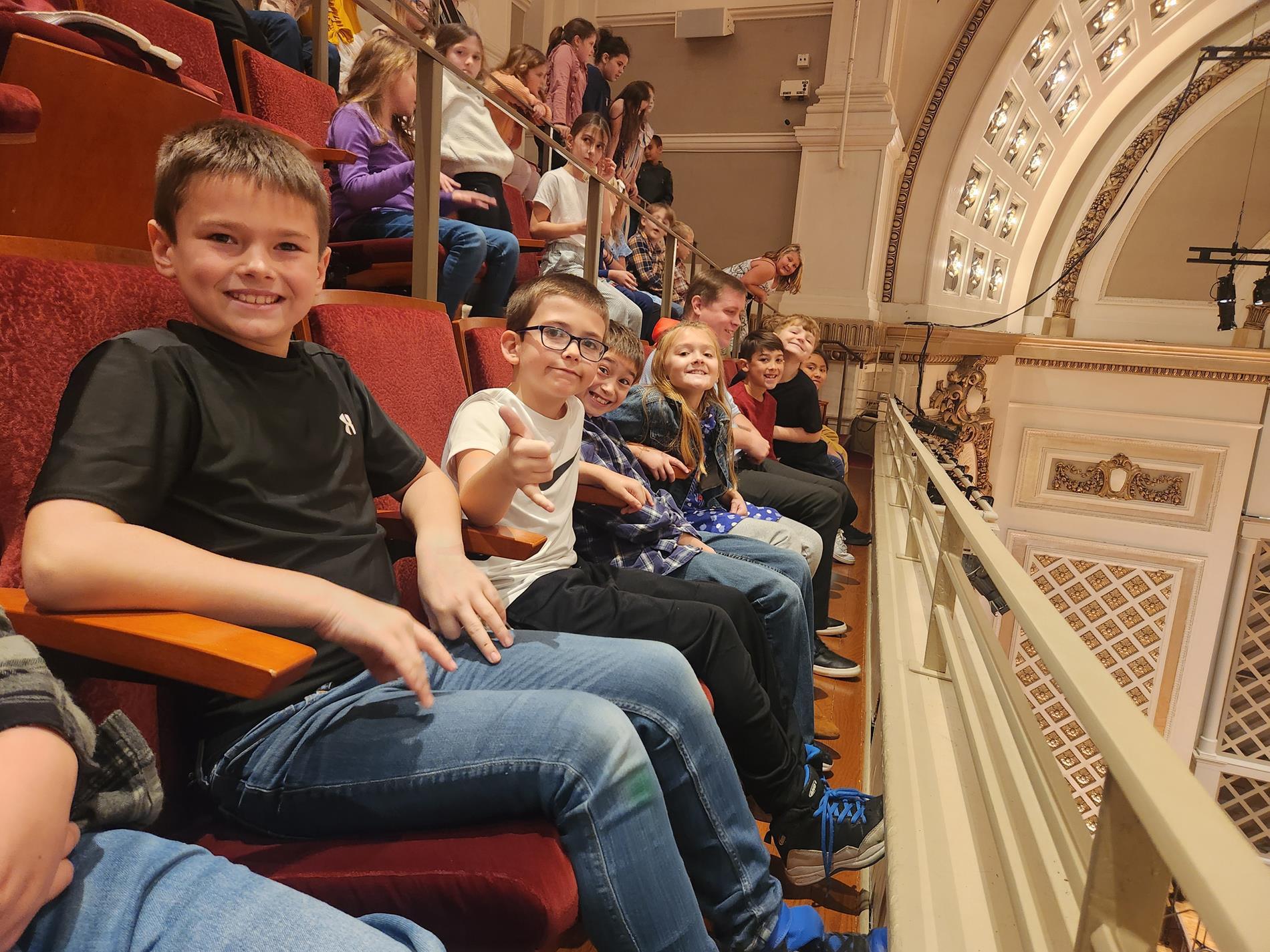 Elementary students sitting in a theater balcony.