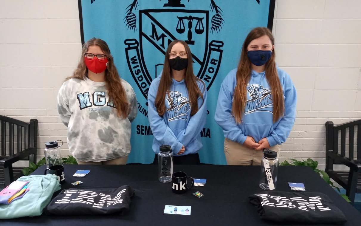 Alexandria Tillman, Lydia Stroud and Reagan Hood standing in from of a table displaying the items they won.