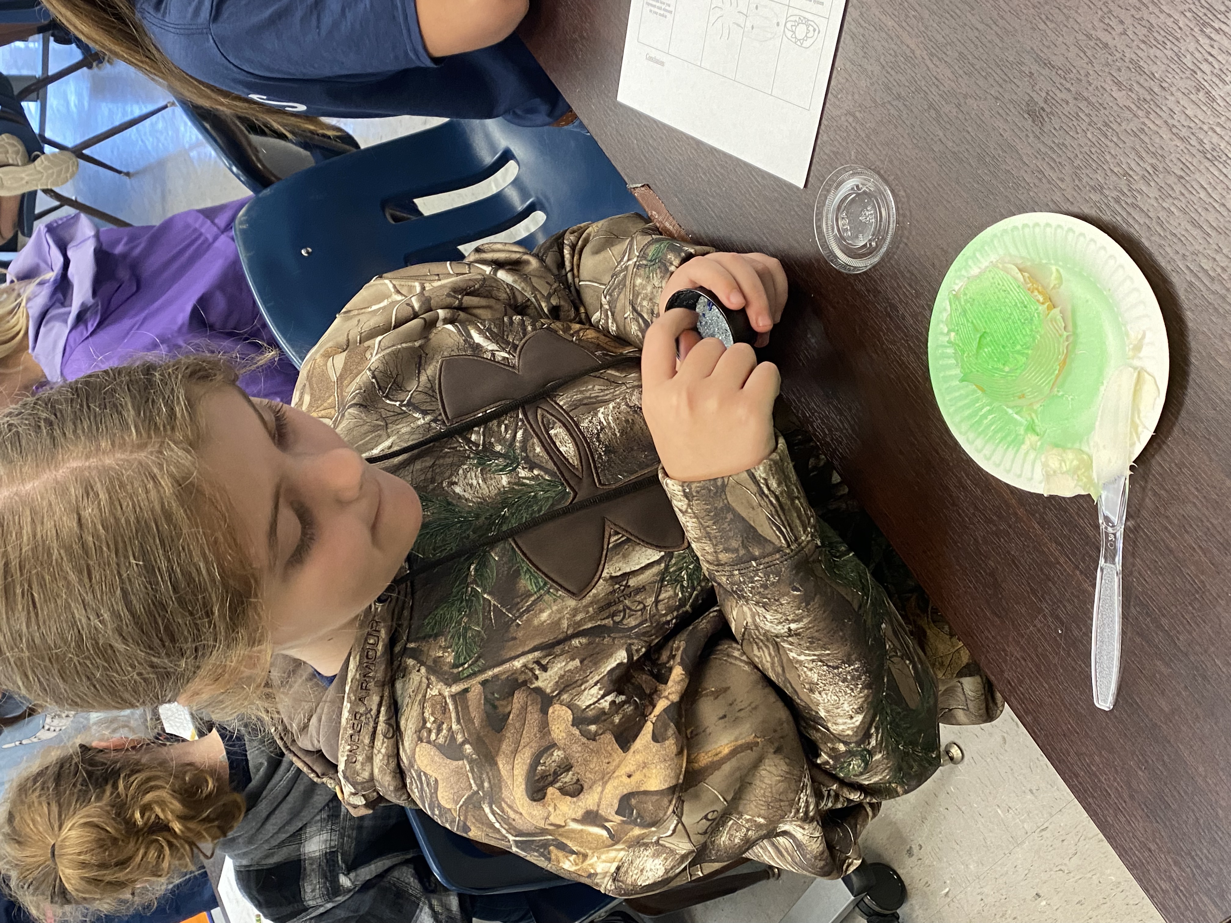 a 5th grade student creating their spiral arms of their galaxy cookie.