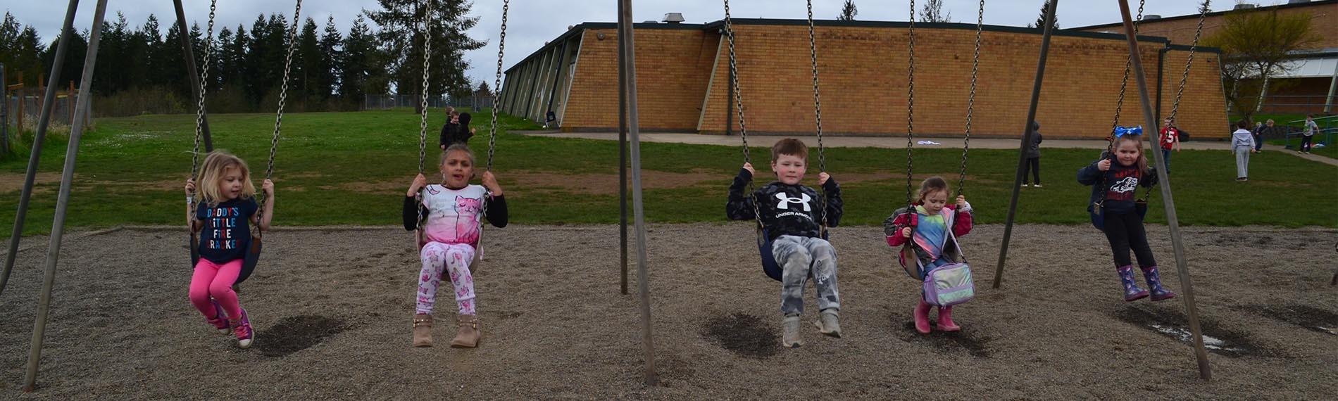 Kindergarten and first grade students swinging at recess