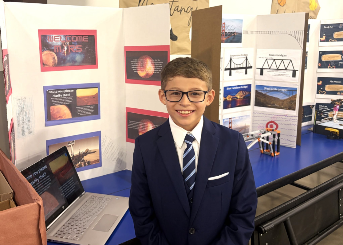 A young male student dressed in a suit showing off his GT project