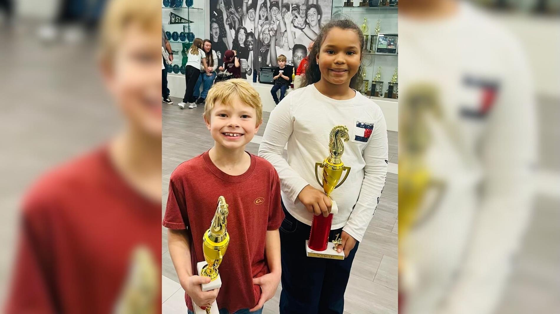 two students holding trophies