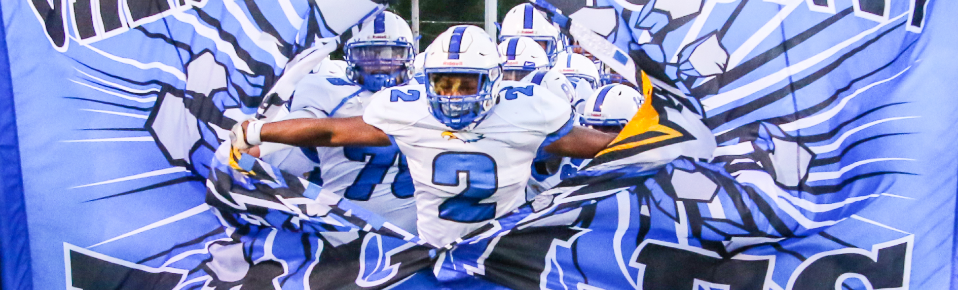 High School Football Player running through the banner