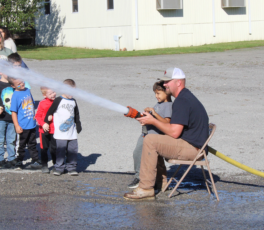 Fire Fighter Andrew Russell helps students with the fire hose