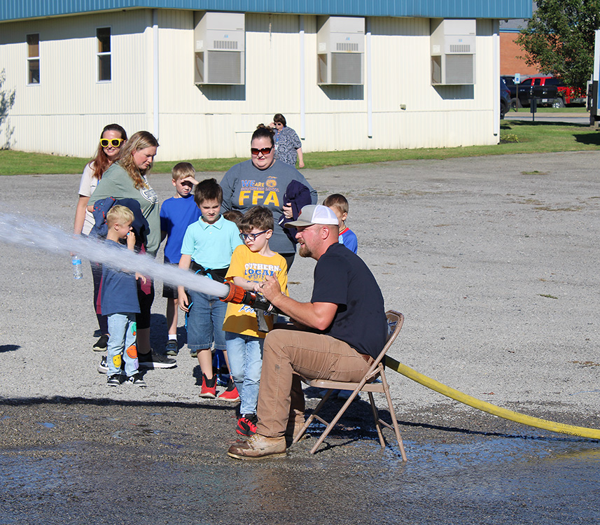 Fire Fighter Andrew Russell helps students with the fire hose