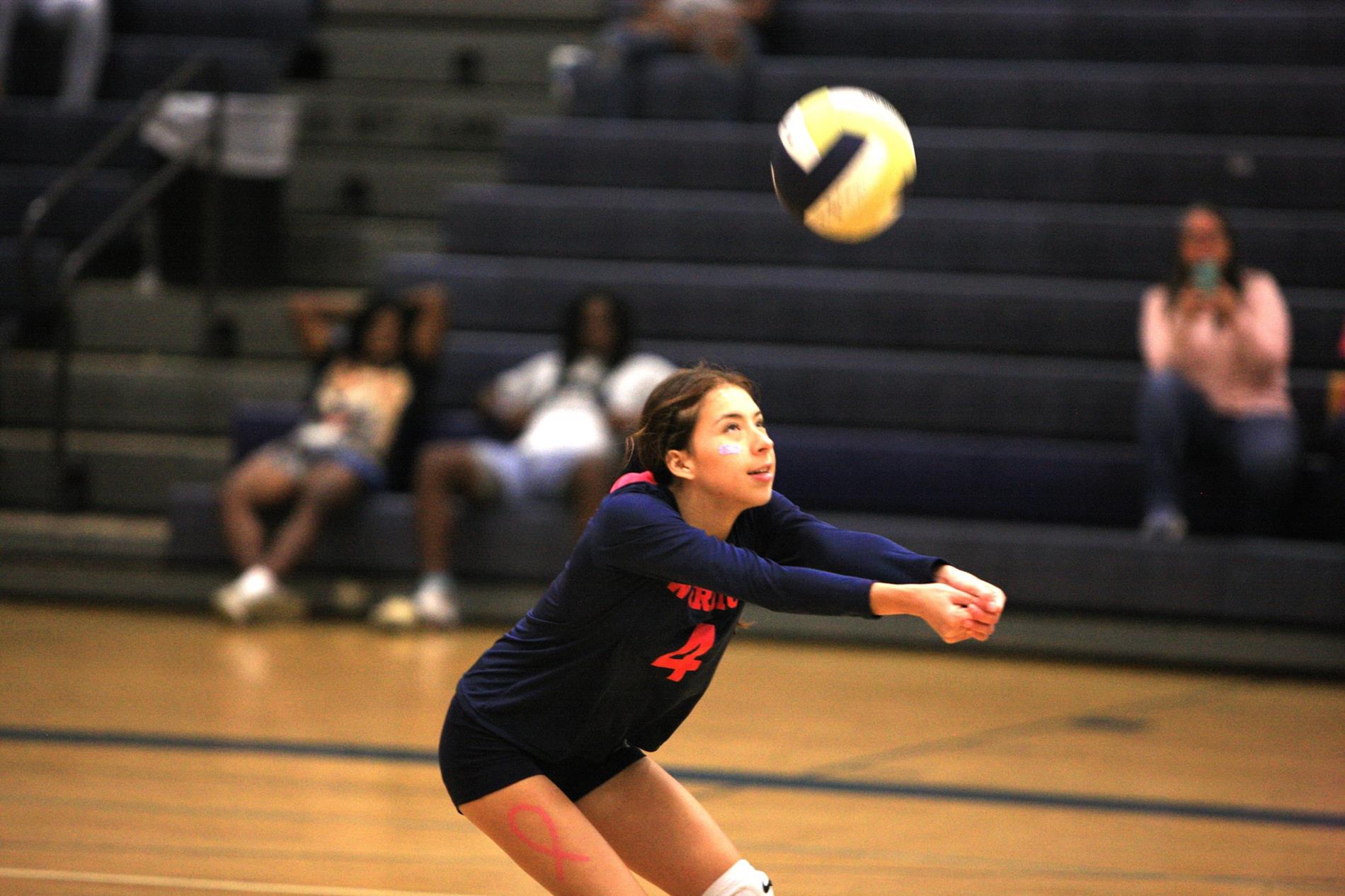 Volleyball player hitting ball over net