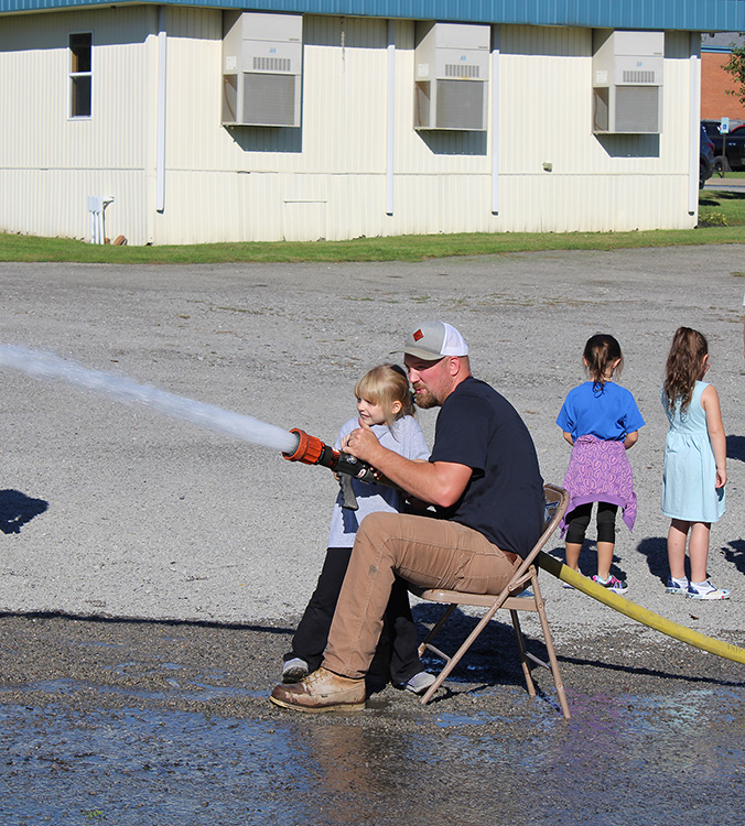 Fire Fighter Andrew Russell helps students with the fire hose