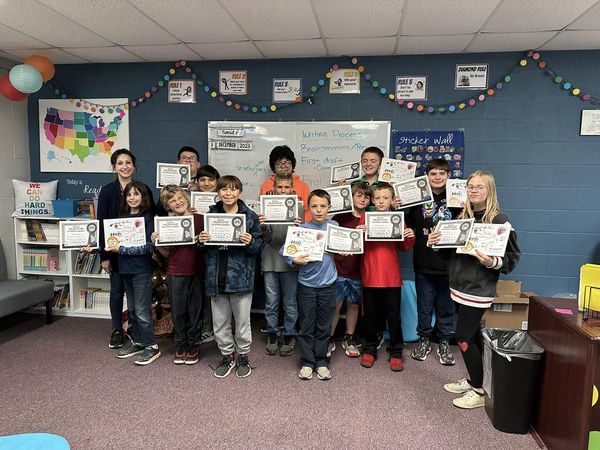 Class poses holding their published book and certificates.