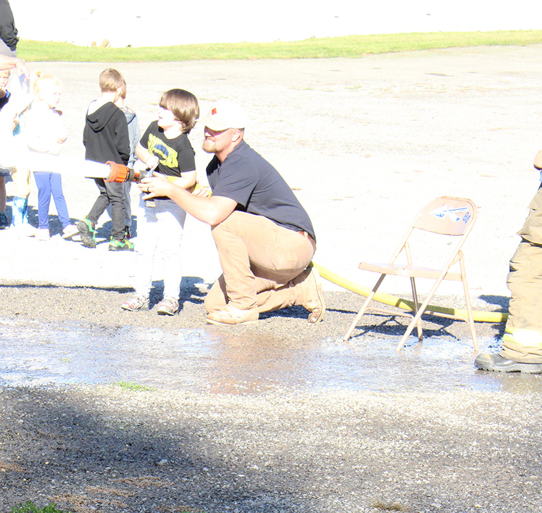 Fire Fighter Andrew Russell helps students with the fire hose