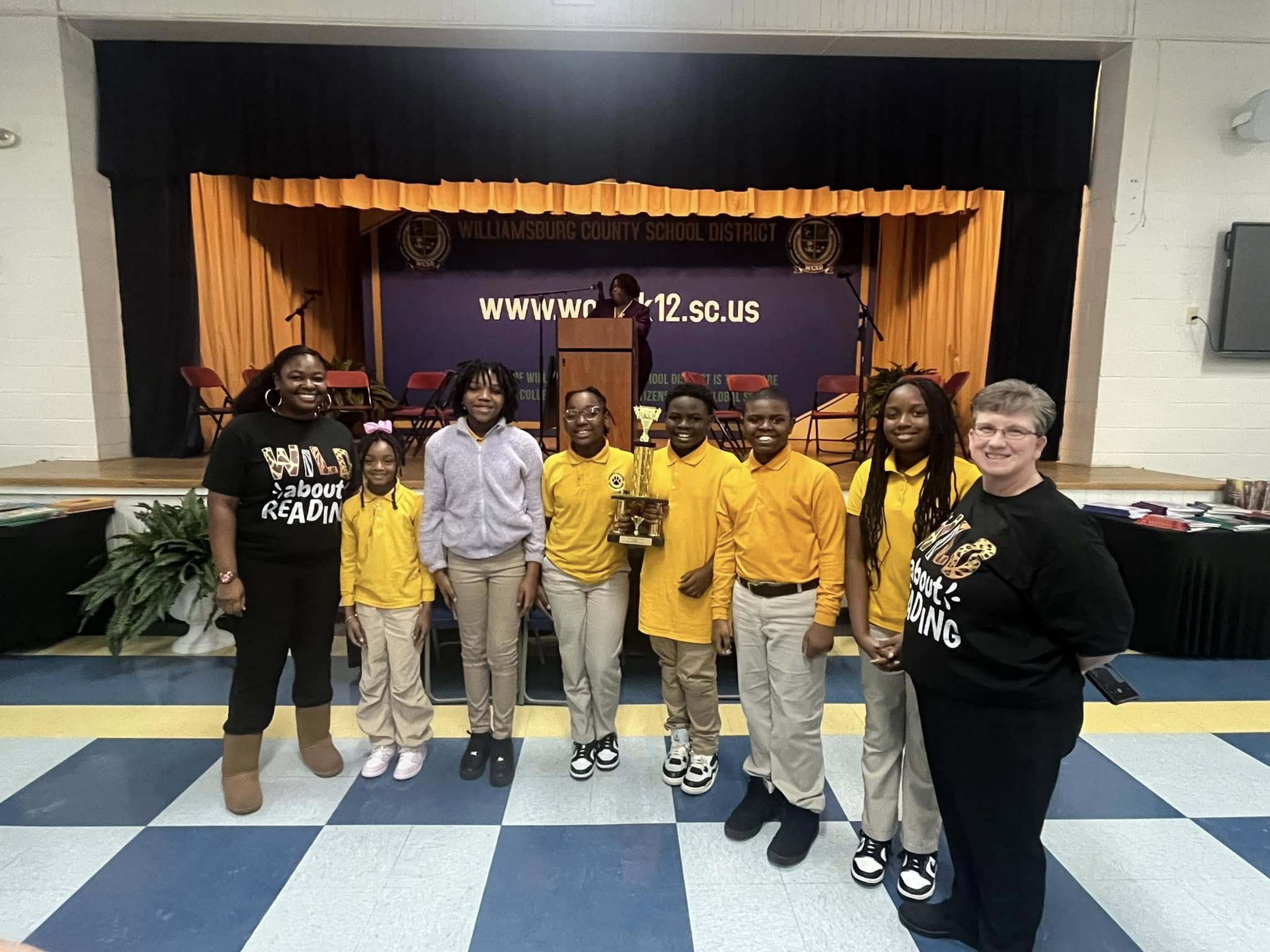 lady standing along with students at battle of the books competition 