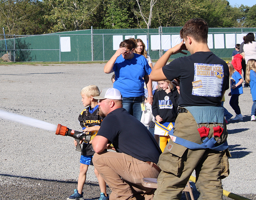 Fire Fighter Andrew Russell helps students with the fire hose