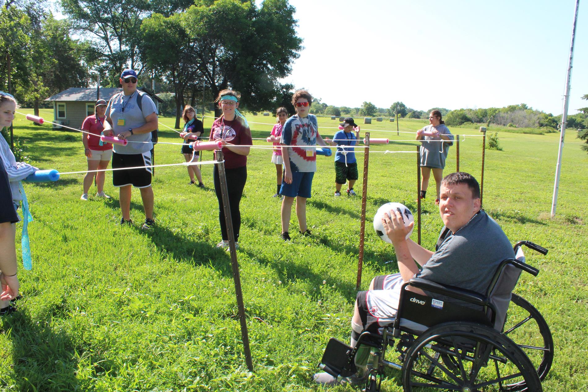 Young adult in a wheelchair watching an outdoor ball game