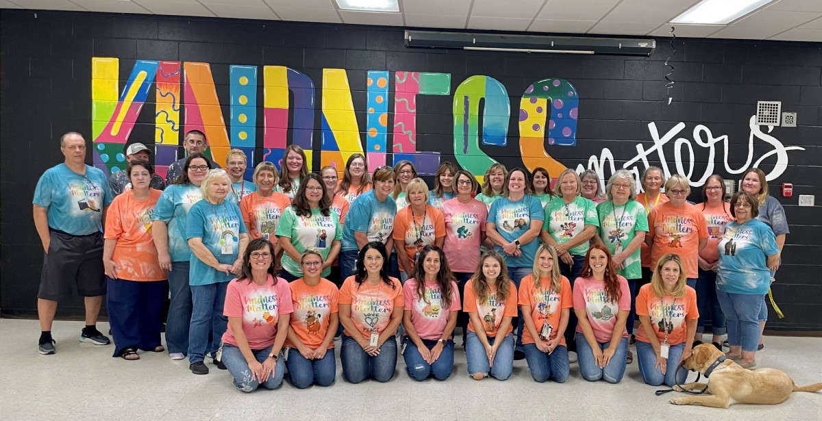 Laurel staff staninding in front of a kindness matters mural