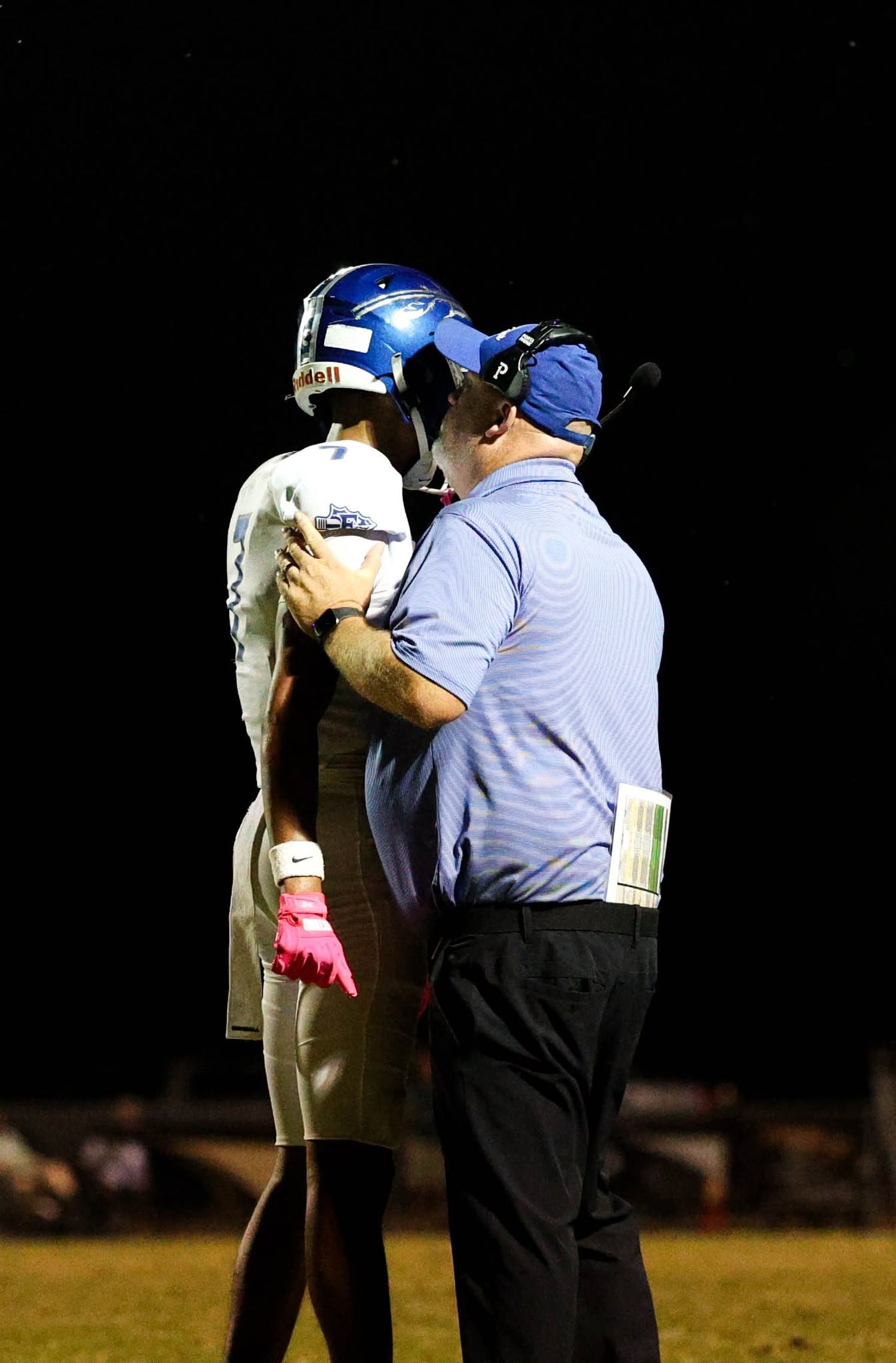 coach Gould speaking to player at a football game