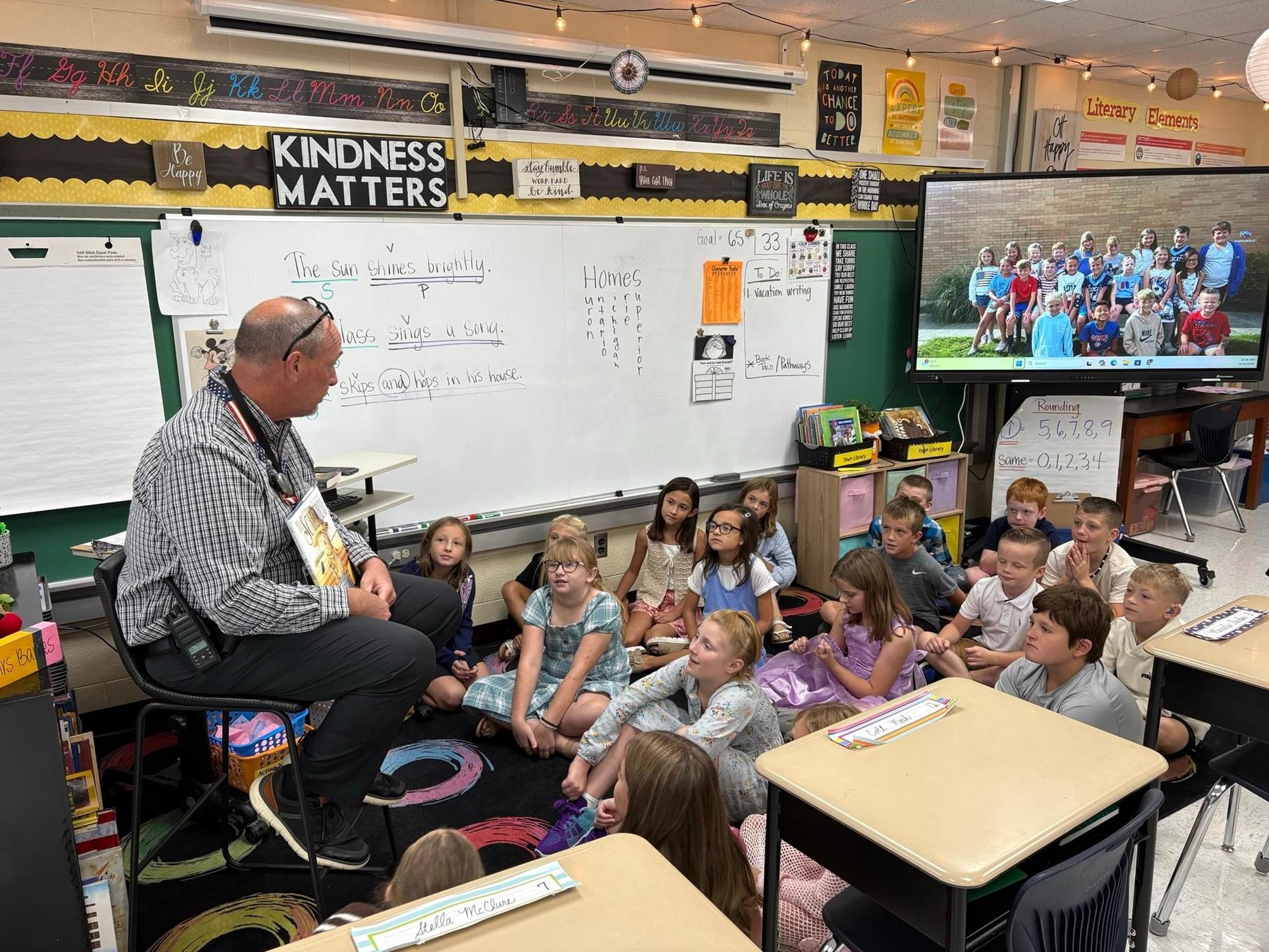 Mr. Piening reads to Mrs. Barnes 3rd grade class.